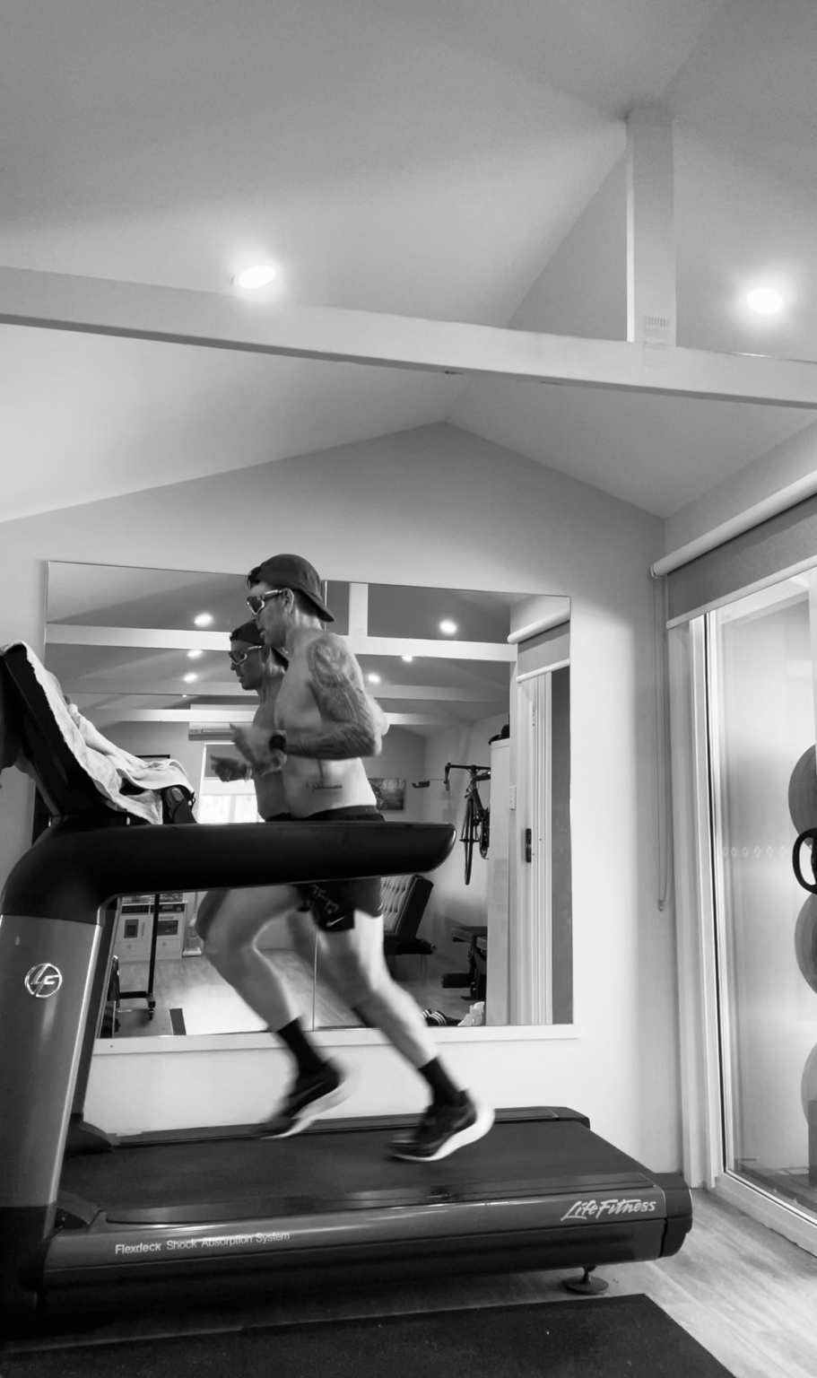 Phillipe running on a treadmill in the home gym, side profile in black and white