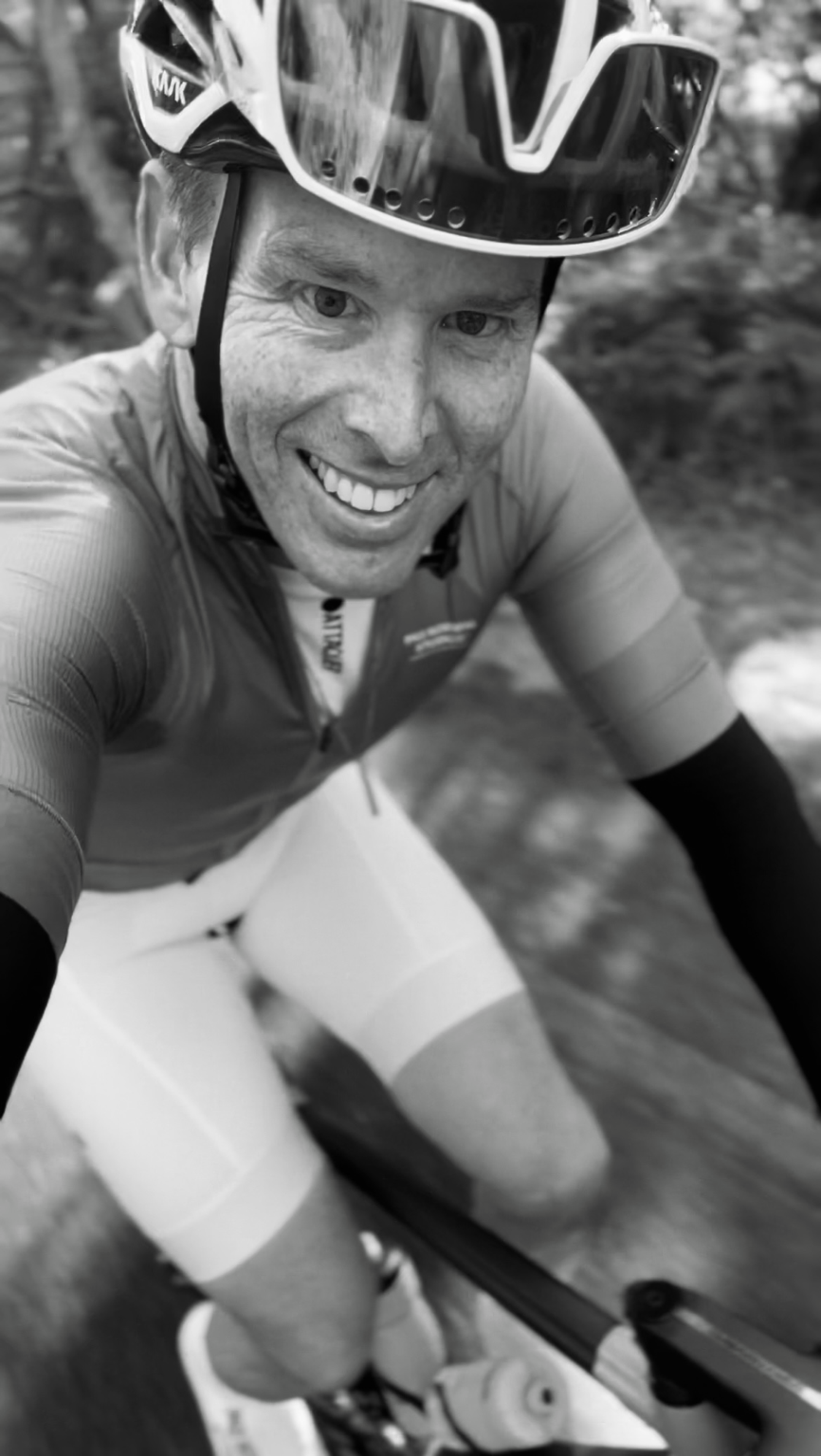 Phillipe smiling while riding outdoors, close-up cycling portrait