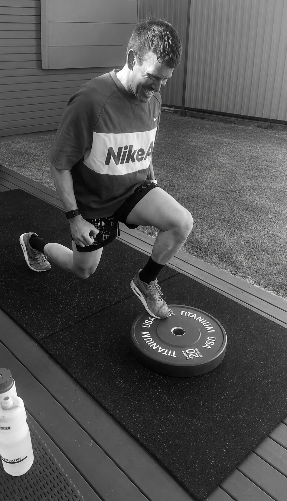 Phillipe performing a single-leg split squat with a bumper plate