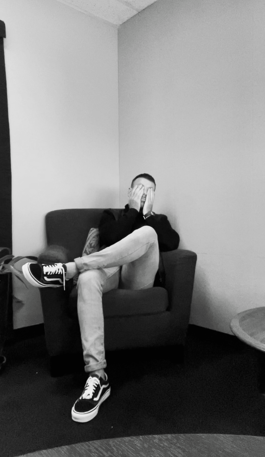 Phillipe sitting in a chair with his hands covering his face
