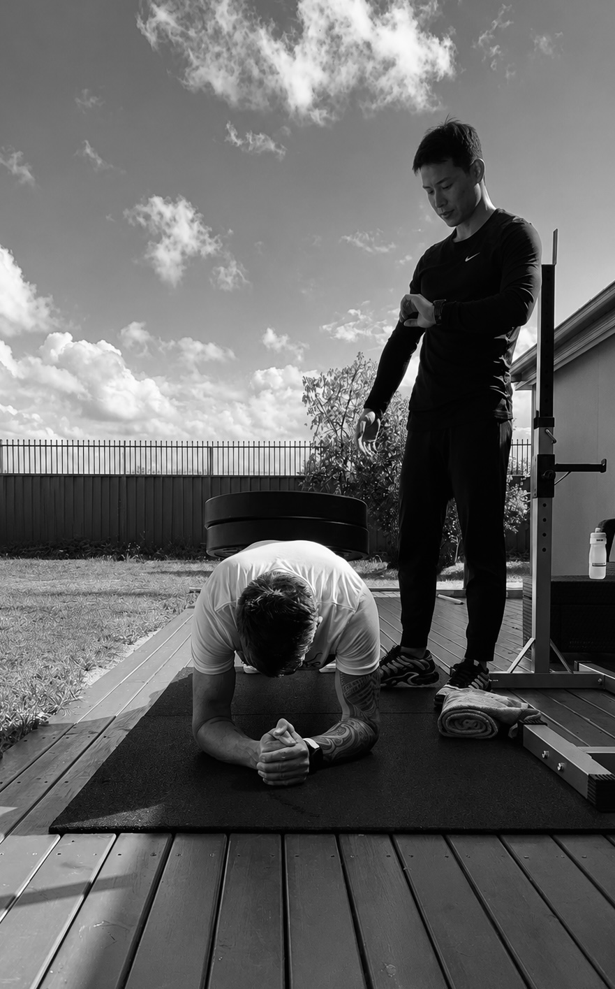 Phillipe holding a weighted plank while a coach checks a stopwatch
